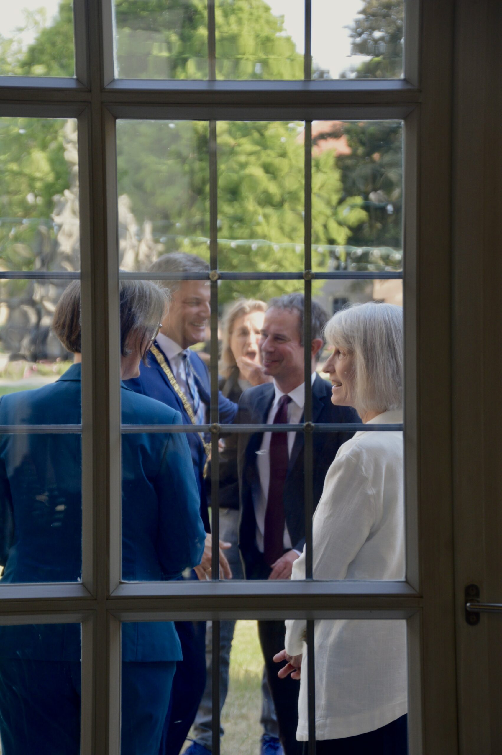 Durch das Fenster fotografiert, Prof. Sikkink im Gespräch mit Professor(innen) und dem Präsidenten